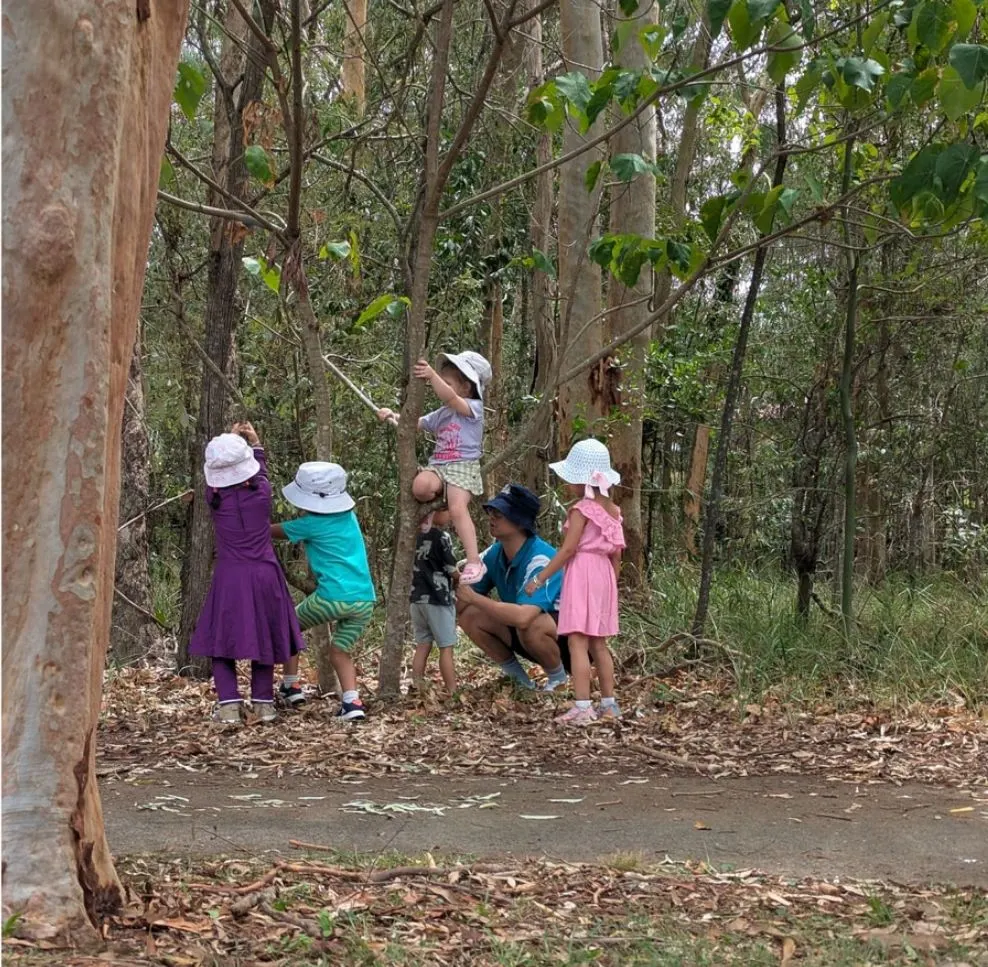 Children mixing water and leaves in pots among the gum leaves