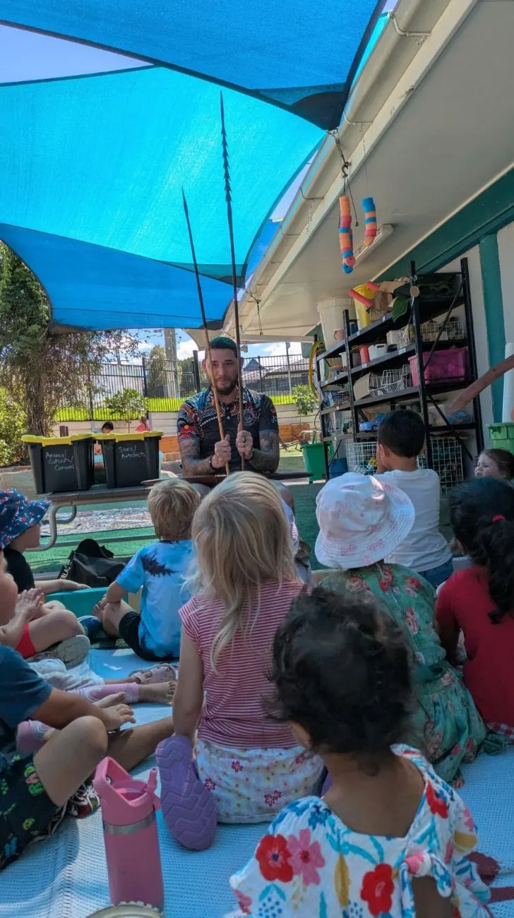 A visitor showing the children traditional artefacts during a session outside