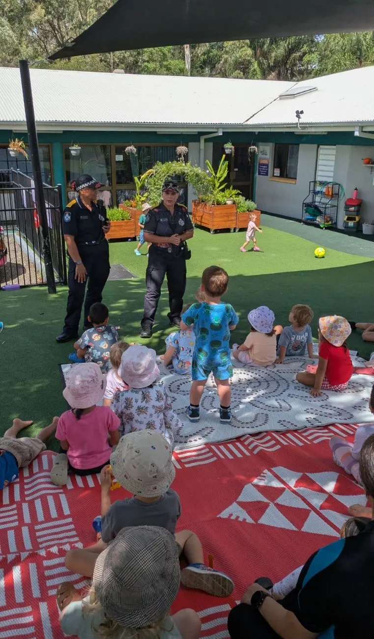 Two police officers talking with the children on the mats outside