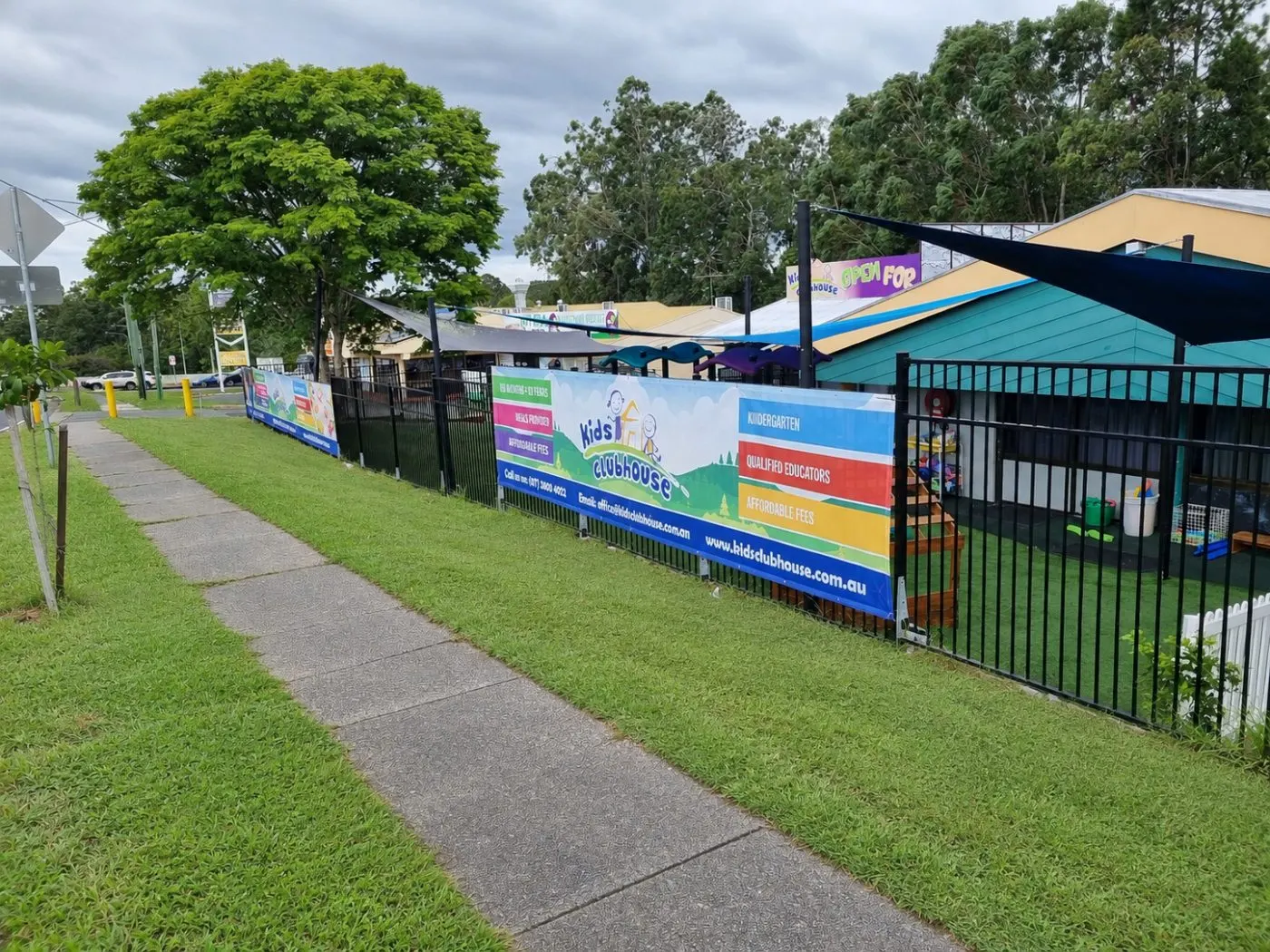 The Kids Clubhouse banners along the front fence, seen from the footpath