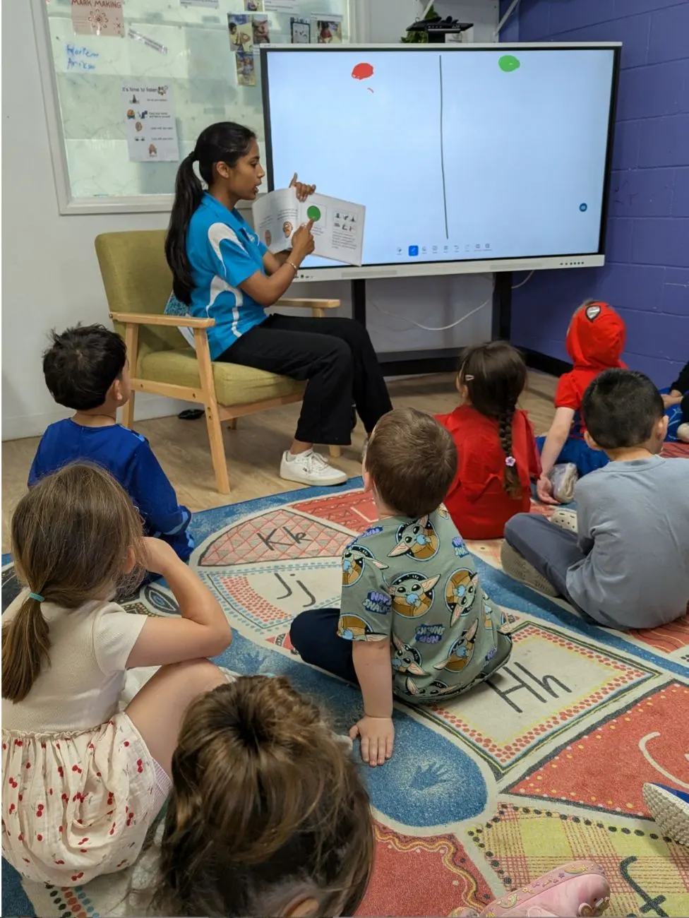 An educator reading to the kindy group during mat time