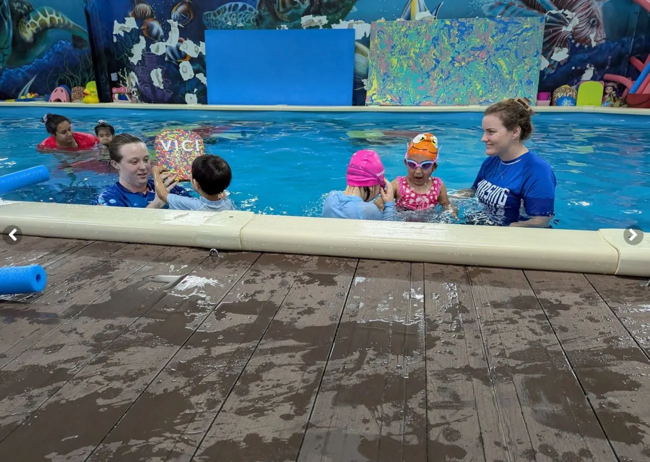 A child practising floating on her back with the teacher supporting her